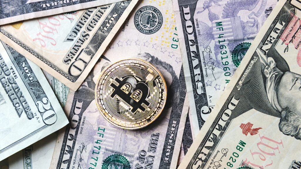 Pildil Ameerika dollarid ning bitcoini münt. Pilt illustreerib teemat: JPMorgan ja krüptoraha - uus partnerlus