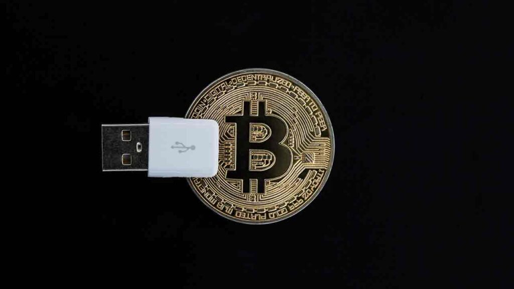 Pildil on Bitcoini münt koos usb-liidesega, mis illustreerib teemat Bitcoin saab 2 tarkvarauuendust